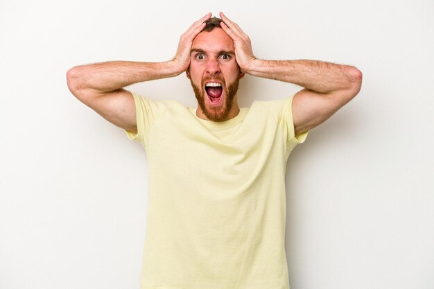 Young caucasian man isolated on white background screaming, very excited, passionate, satisfied with something.