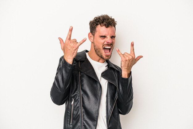 Young caucasian man isolated on white background showing a horns gesture as a revolution concept.