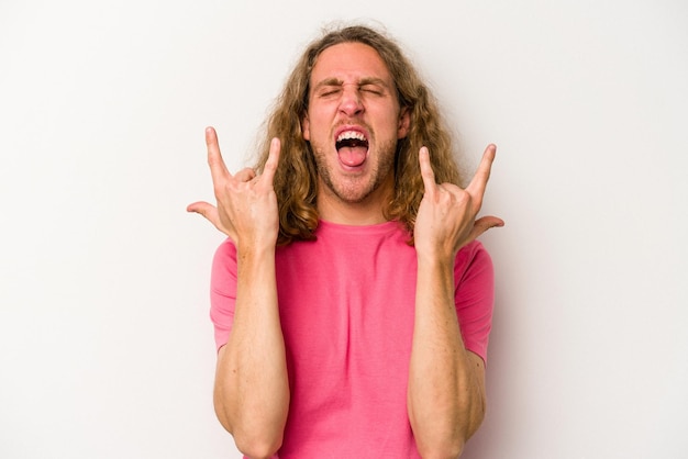 Young caucasian man isolated on white background showing a horns gesture as a revolution concept