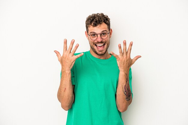 Young caucasian man isolated on white background showing number ten with hands.
