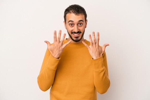 Young caucasian man isolated on white background showing number ten with hands.