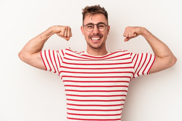 Young caucasian man isolated on white background showing strength gesture with arms, symbol of feminine power