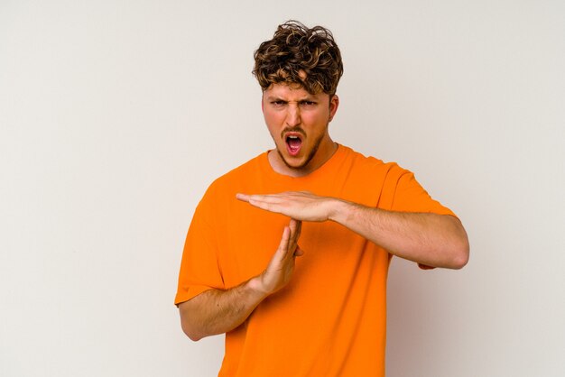 Young caucasian man isolated on white background showing a timeout gesture.