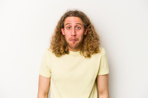 Young caucasian man isolated on white background shrugs shoulders and open eyes confused