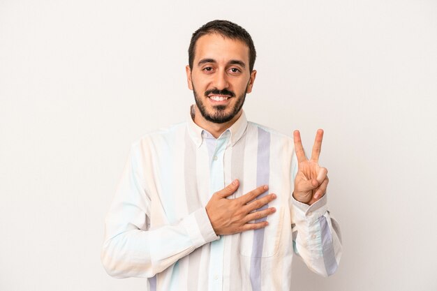 Young caucasian man isolated on white background taking an oath, putting hand on chest.