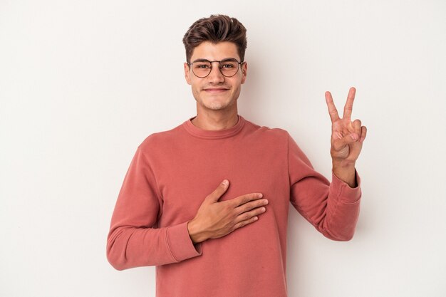 Young caucasian man isolated on white background taking an oath, putting hand on chest.