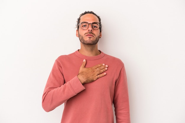 Young caucasian man isolated on white background taking an oath, putting hand on chest.