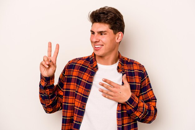 Young caucasian man isolated on white background taking an oath putting hand on chest