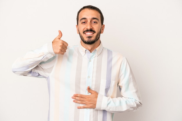 Young caucasian man isolated on white background touches tummy, smiles gently, eating and satisfaction concept.