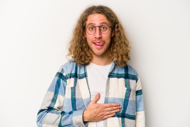 Young caucasian man isolated on white background touches tummy smiles gently eating and satisfaction concept