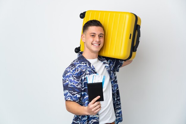 Young caucasian man isolated on white background in vacation with suitcase and passport