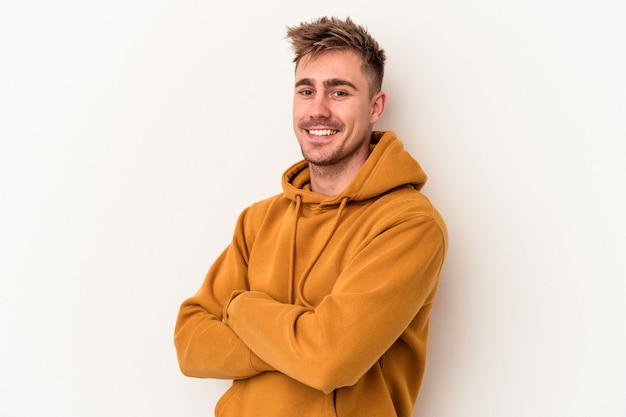 Young caucasian man isolated on white background who feels confident, crossing arms with determination.