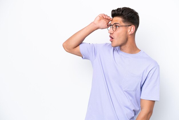 Young caucasian man isolated on white background with surprise expression while looking side