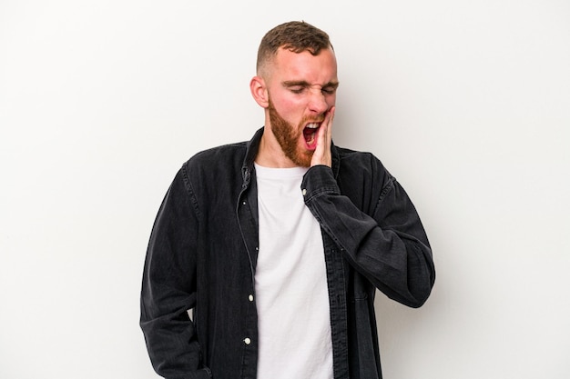 Young caucasian man isolated on white background yawning showing a tired gesture covering mouth with hand