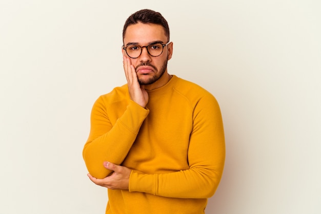 Young caucasian man isolated on white blows cheeks, has tired expression. Facial expression concept.