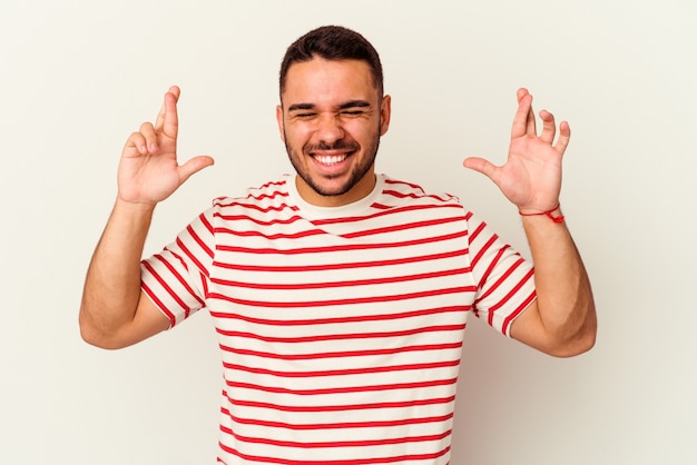 Young caucasian man isolated on white crossing fingers for having luck