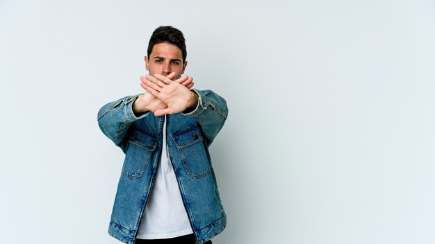 Young caucasian man isolated on white wall doing a denial gesture