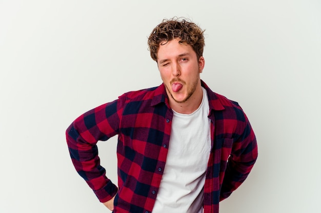 Young caucasian man isolated on white wall funny and friendly sticking out tongue.