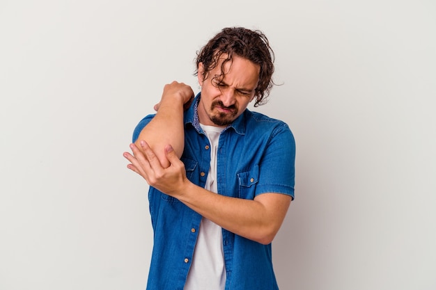 Photo young caucasian man isolated on white wall massaging elbow, suffering after a bad movement.