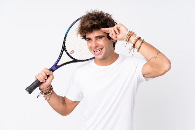 Молодой кавказский человек над изолированной белой стеной играя теннис