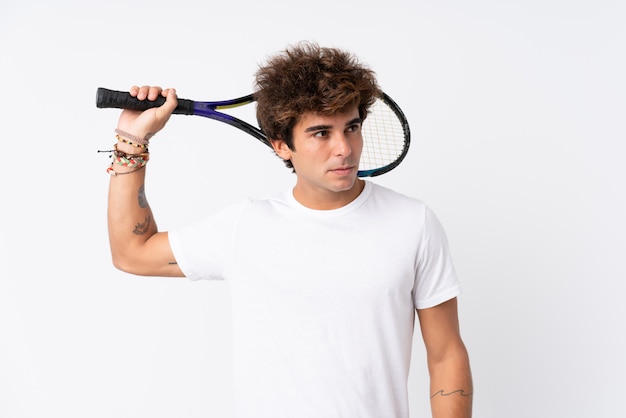 Young caucasian man over isolated white wall playing tennis