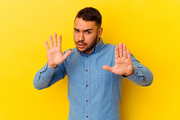 Young caucasian man isolated on yellow background being shocked due to an imminent danger