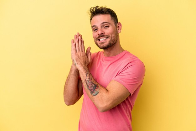 Young caucasian man isolated on yellow background feeling energetic and comfortable, rubbing hands confident.