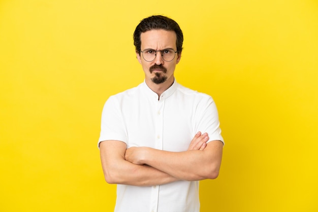 Young caucasian man isolated on yellow background feeling upset