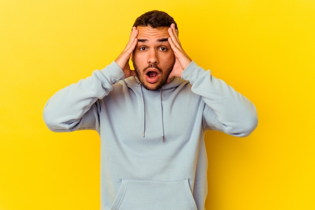 Young caucasian man isolated on yellow background having fun covering half of face with palm.