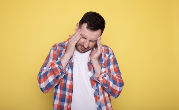 Young caucasian man isolated on yellow background having a head ache touching front of the face