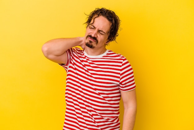 Young caucasian man isolated on yellow background having a neck pain due to stress, massaging and touching it with hand.