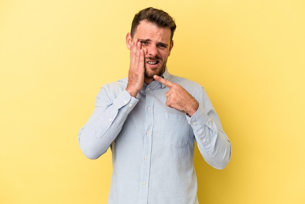 Young caucasian man isolated on yellow background having a strong teeth pain molar ache