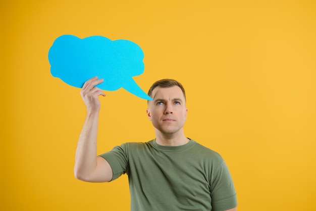 Young caucasian man isolated on yellow background holding a
thinking speech bubble and doing ok sign