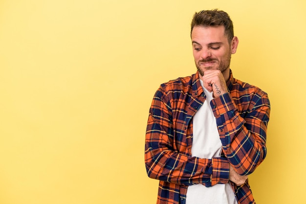 Young caucasian man isolated on yellow background looking sideways with doubtful and skeptical expression.