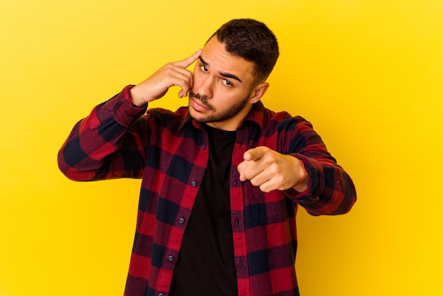 Young caucasian man isolated on yellow background pointing temple with finger, thinking, focused on a task.