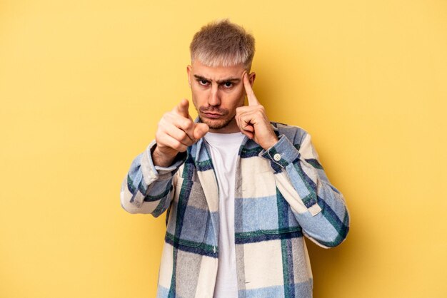 Young caucasian man isolated on yellow background pointing temple with finger, thinking, focused on a task.