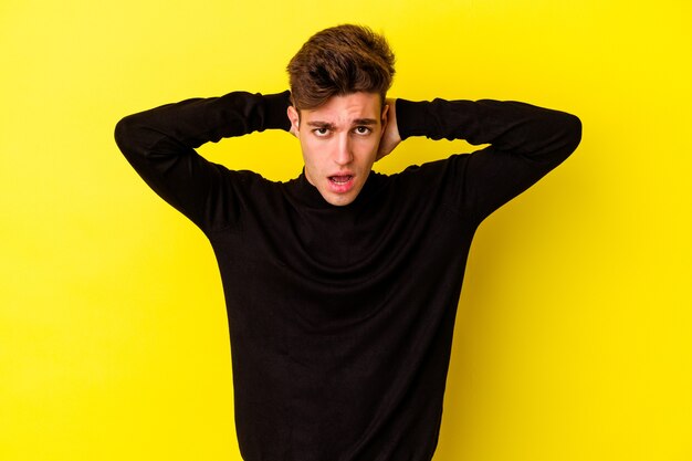 Young caucasian man isolated on yellow background screaming, very excited, passionate, satisfied with something.