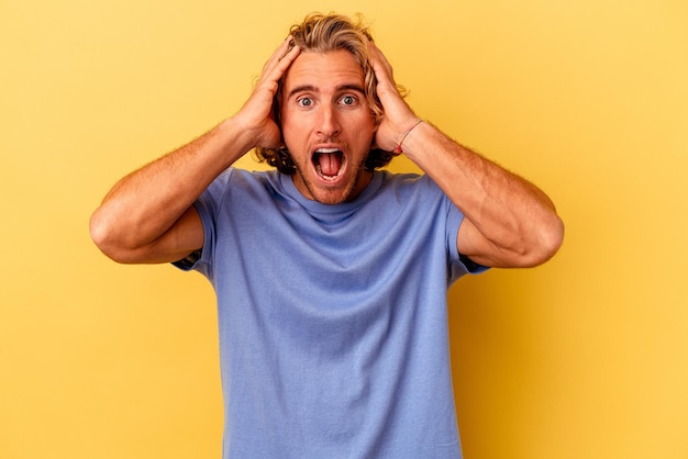 Young caucasian man isolated on yellow background screaming, very excited, passionate, satisfied with something.