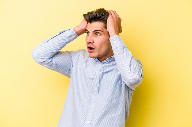 Young caucasian man isolated on yellow background screaming, very excited, passionate, satisfied with something.