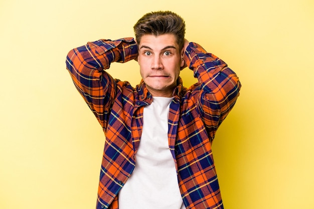 Young caucasian man isolated on yellow background screaming with rage.