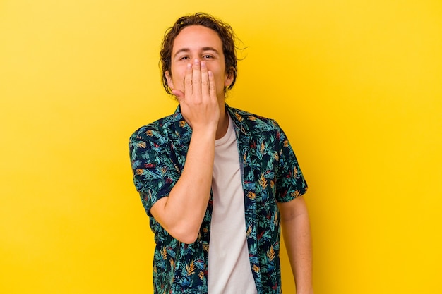 Young caucasian man isolated on yellow background shocked, covering mouth with hands, anxious to discover something new.