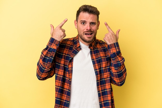 Young caucasian man isolated on yellow background showing a disappointment gesture with forefinger