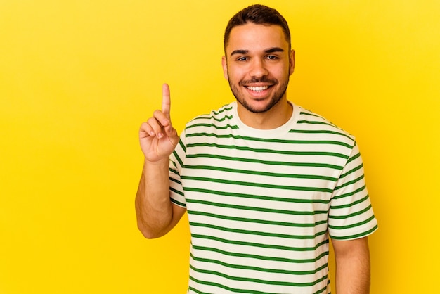 Young caucasian man isolated on yellow background showing number one with finger.