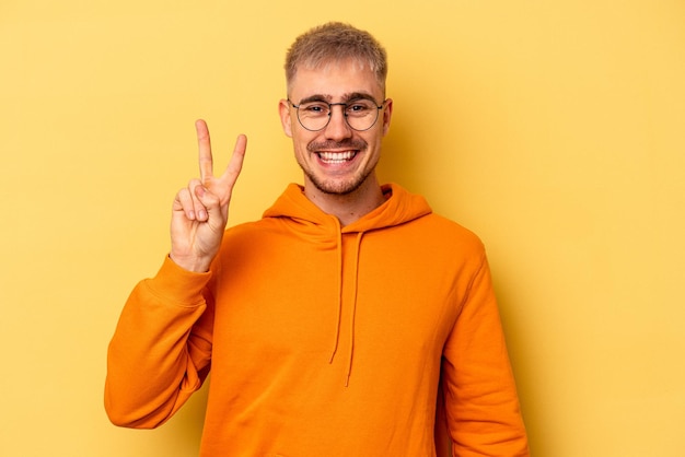 Young caucasian man isolated on yellow background showing number two with fingers.