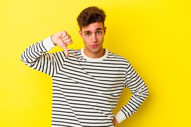 Young caucasian man isolated on yellow background showing thumb down, disappointment concept.