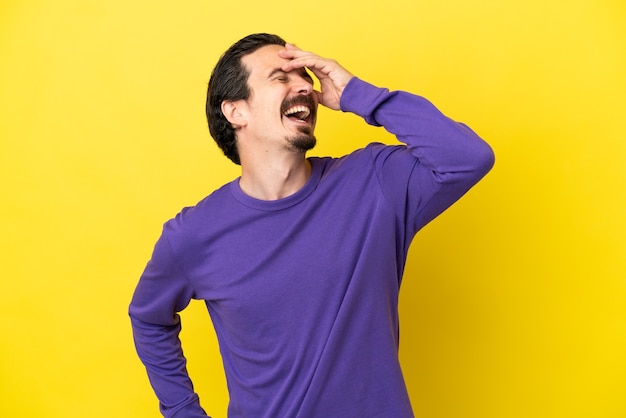 Young caucasian man isolated on yellow background smiling a lot