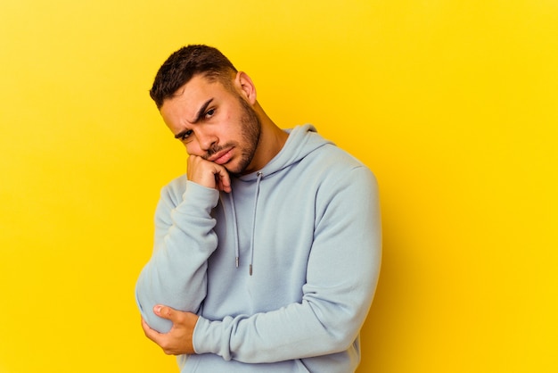 Young caucasian man isolated on yellow background tired of a repetitive task.