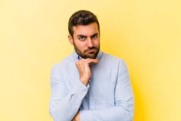 Young caucasian man isolated on yellow background tired of a repetitive task