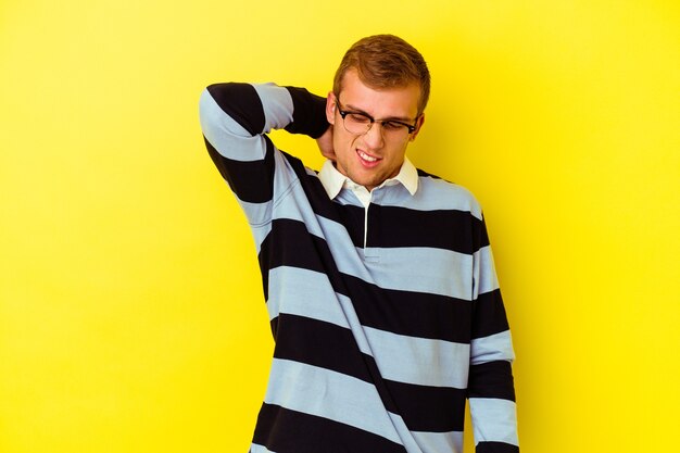 Young caucasian man isolated on yellow background tired and very sleepy keeping hand on head