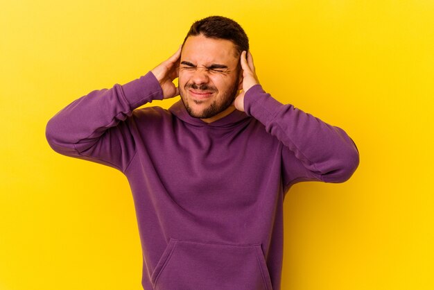 Young caucasian man isolated on yellow background touching temples and having headache.